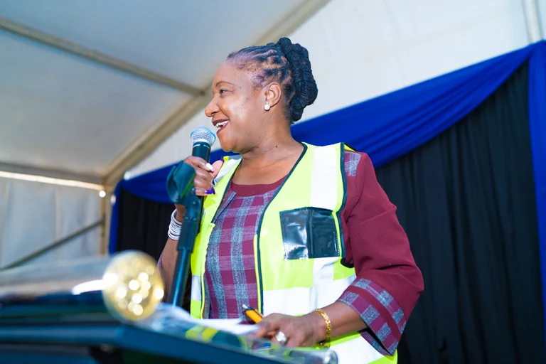 A speaker in a reflective vest addresses the Greenhills title deed handover